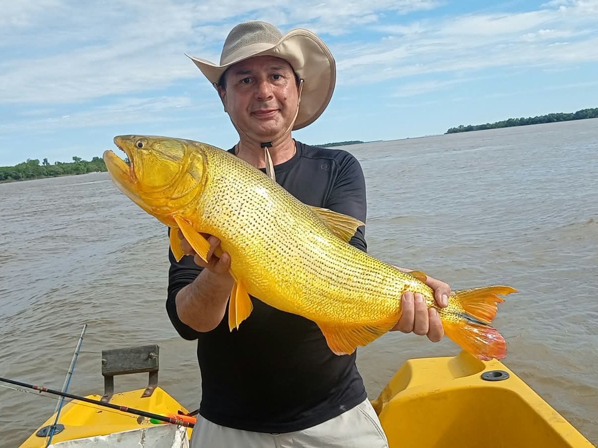 Pescador sosteniendo un dorado en la lancha, Esquina, Corrientes