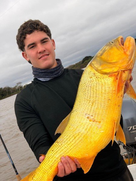 Joven pescador sostiene un dorado enorme en el río, Esquina, Corrientes