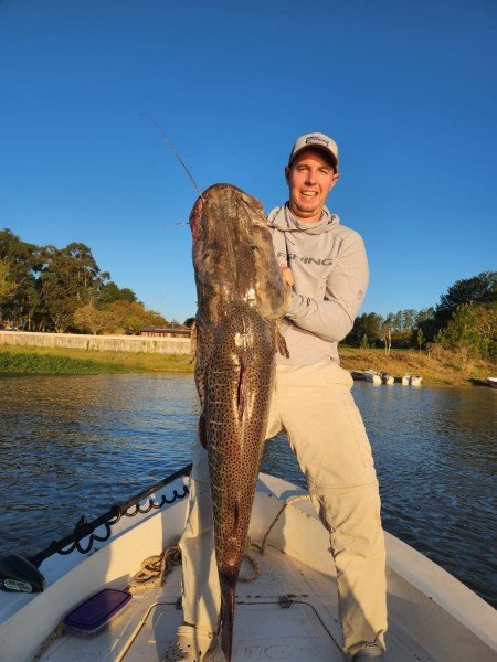 Pescador sostiene en vertical un surubí en la proa de la lancha, Esquina, Corrientes