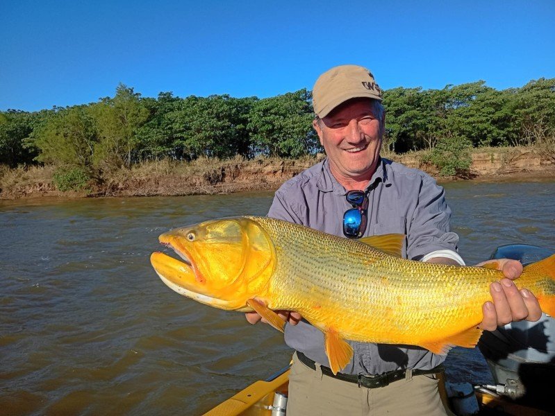 Pescador sonriente con un dorado, monte de la costa de fondo, Esquina, Corrientes