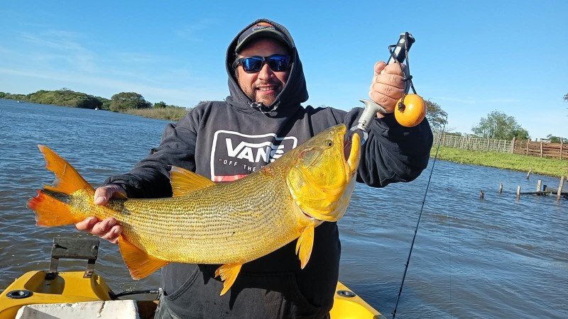 Pescador con un dorado y la caña, costa del río de fondo, Esquina, Corrientes