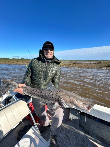 Pescador con campera verde sostiene un surubí en la lancha, Esquina, Corrientes
