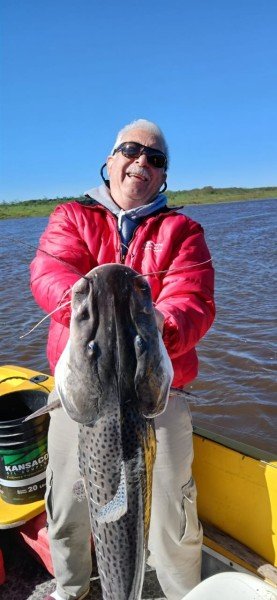 Pescador con campera roja sostiene un surubí, Esquina, Corrientes