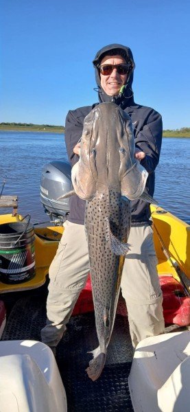 Pescador con capucha sostiene un surubí en la lancha, Esquina, Corrientes